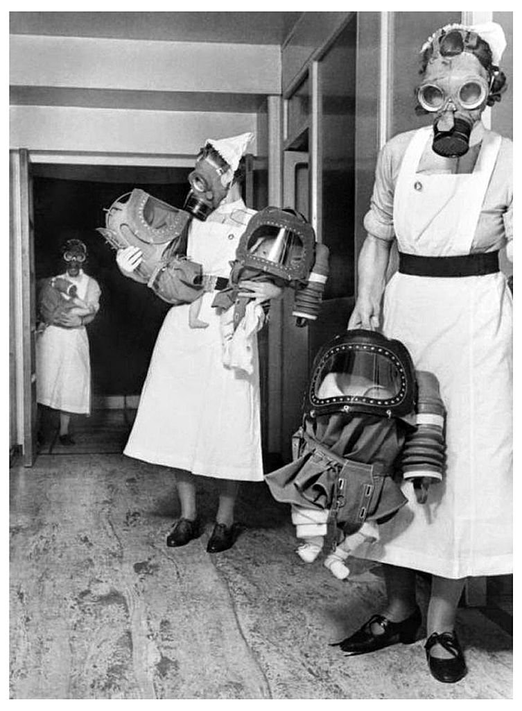 Photograph of three nurses testing gas masks on babies at an English hospital dated 1940. 