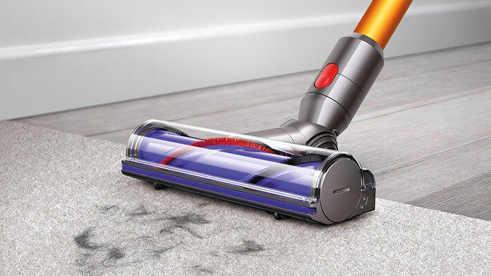 A close-up of the Dyson V8 cordless vacuum head on a carpeted floor.