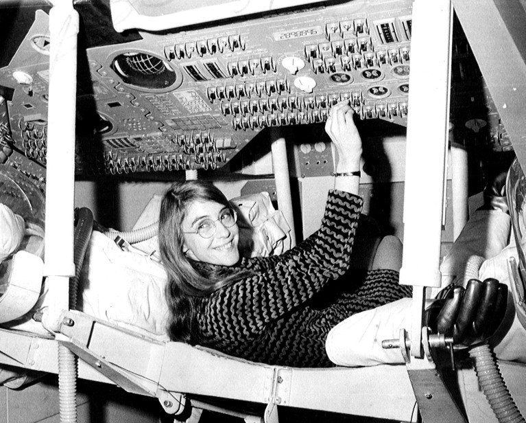 Margaret Hamilton sits at the instrument panel in a mock-up of an Apollo command module at MIT Instrumentation Laboratory.