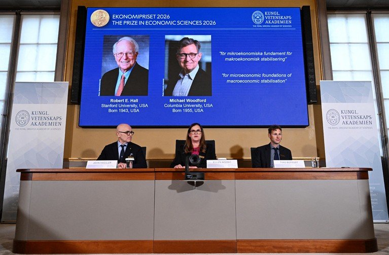 The three person panel at the Royal Academy of Sciences in Sweden, seated in front of a screen showing the joint winners of the 2026 Nobel prize in Economics.