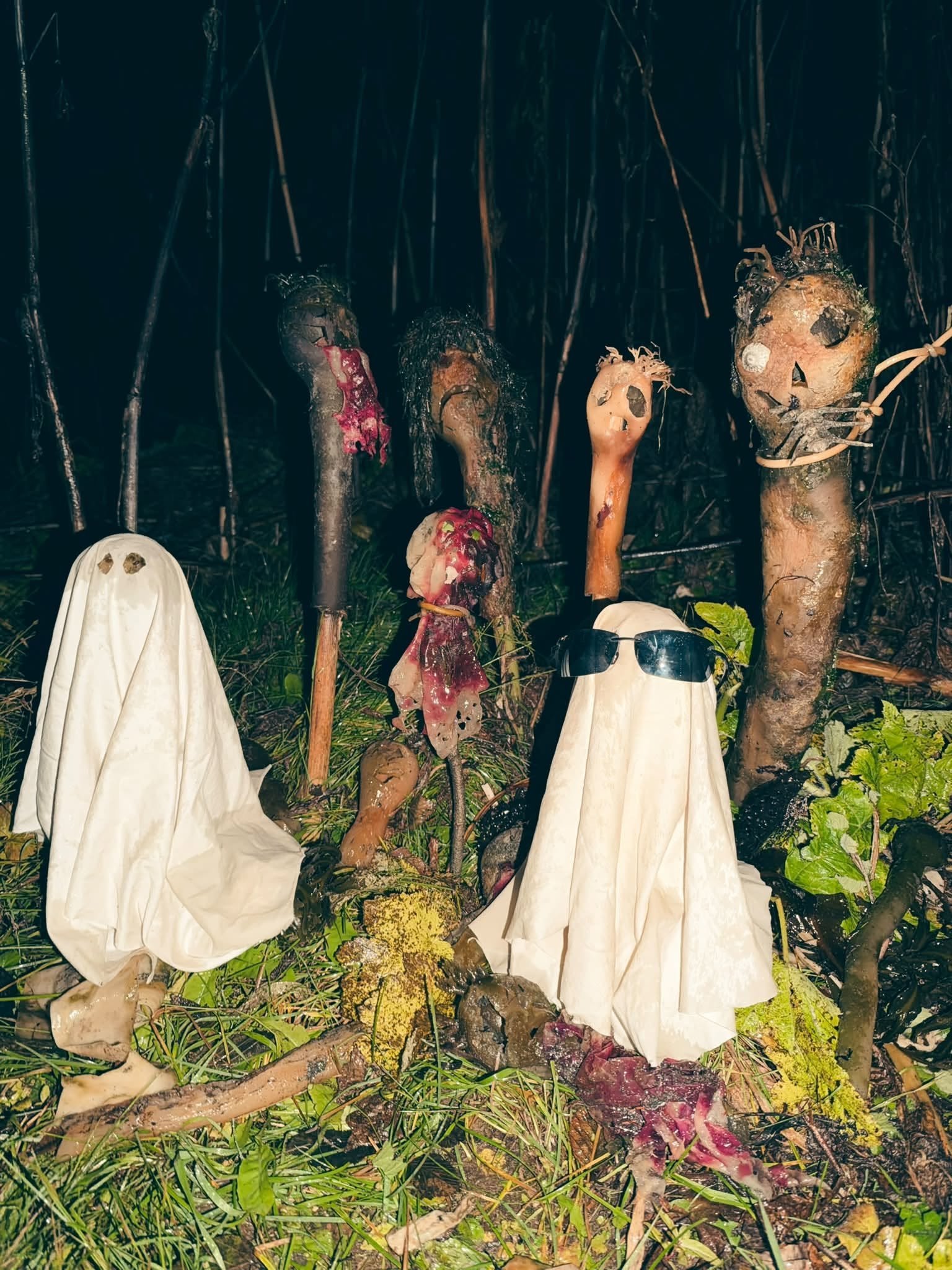creepy sculptures made of kelp and two ghosts sit in a yard