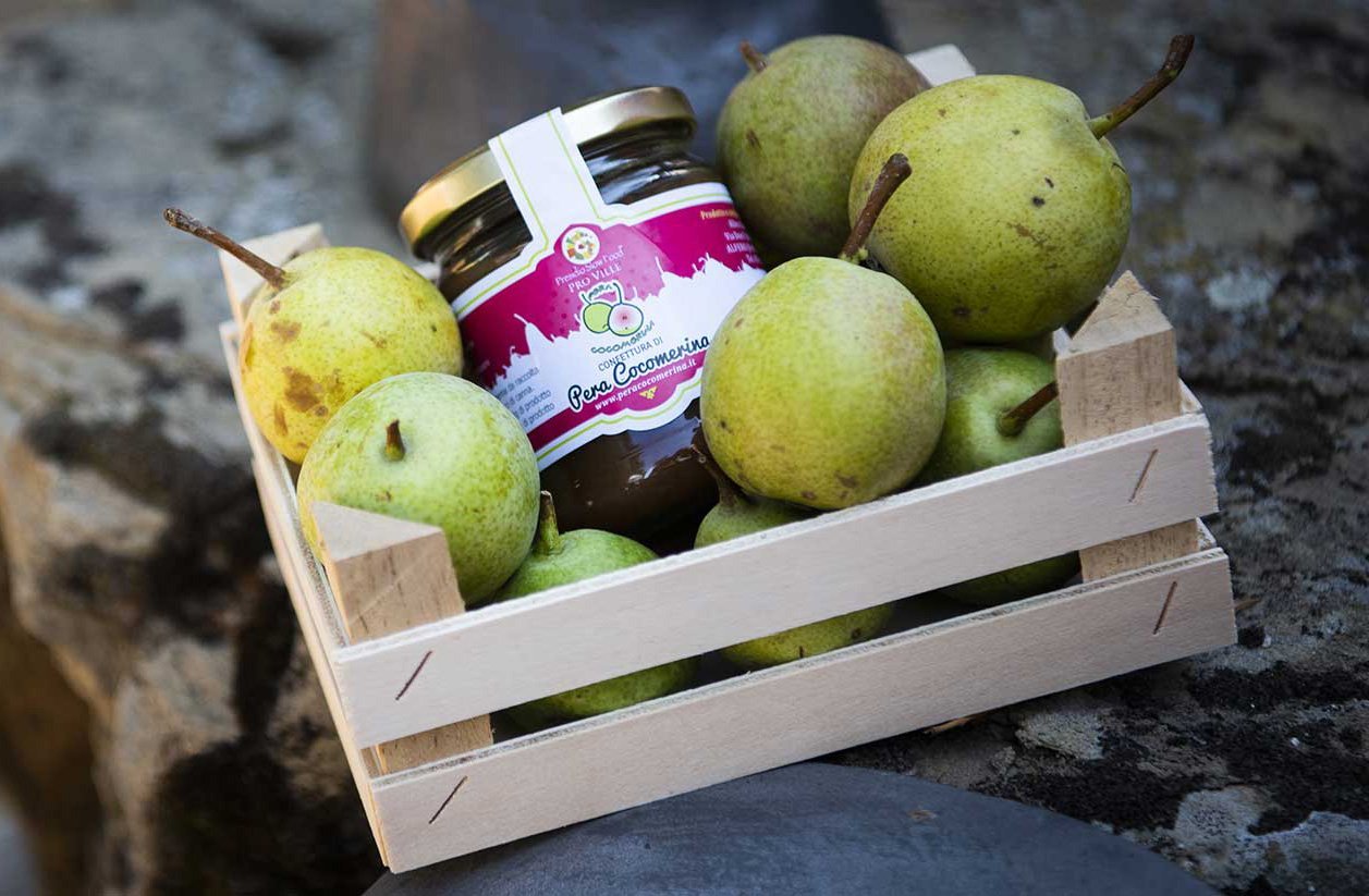 Wooden crate with small green pears and a jar of marmalade.